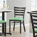 A Lancaster Table & Seating ladder back chair with a seafoam green cushion.