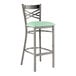 A Lancaster Table & Seating black metal cross back bar stool with a seafoam green vinyl padded seat.