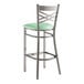 A Lancaster Table & Seating metal bar stool with a seafoam green padded seat.
