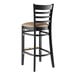 A black Lancaster Table & Seating wood ladder back bar stool with a taupe vinyl seat.