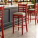 A Lancaster Table & Seating mahogany wood bar stool with taupe vinyl seats.