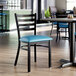 A black ladder back chair with a blue vinyl padded seat, designed for dining or restaurant use.
