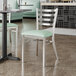 A Lancaster Table & Seating ladder back chair with a seafoam vinyl padded seat on a table in a restaurant.