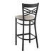 A black Lancaster Table & Seating bar stool with a light gray cushion.