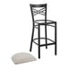 A black Lancaster Table & Seating cross back bar stool with a light gray cushion on the seat.