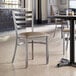 A Lancaster Table & Seating ladder back chair with a taupe vinyl padded seat on a table in a restaurant.