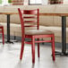 A Lancaster Table & Seating mahogany wood chair with a taupe vinyl seat on a table in a restaurant.