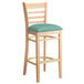 A Lancaster Table & Seating wooden bar stool with a seafoam vinyl cushion.