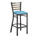 A Lancaster Table & Seating metal ladder back bar stool with a blue vinyl padded seat.