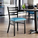 A black ladder back chair with a blue vinyl padded seat.