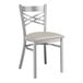 A Lancaster Table & Seating silver metal cross back chair with a light gray cushion.