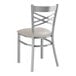 A Lancaster Table & Seating silver metal cross back chair with a light gray cushioned seat.