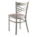 A Lancaster Table & Seating silver metal cross back chair with a light gray vinyl padded seat.