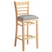 A Lancaster Table & Seating wooden bar stool with a light gray cushion.