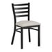 A black Lancaster Table & Seating metal ladder back chair with a light gray vinyl padded seat.