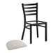 A black Lancaster Table & Seating ladder back chair with a light gray vinyl padded seat.