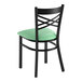 A black metal cross back chair with a seafoam green vinyl padded seat.