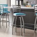 A group of three Lancaster Table & Seating blue vinyl padded bar stools with clear coat finish on the ladder backs.