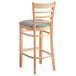 A Lancaster Table & Seating wooden bar stool with a light gray vinyl seat.