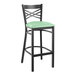 A Lancaster Table & Seating black cross back bar stool with a seafoam green vinyl padded seat.