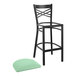 A black Lancaster Table & Seating bar stool with a seafoam green cushion.