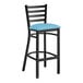 A Lancaster Table & Seating black ladder back bar stool with a blue vinyl padded seat.