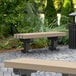 A MasonWays backless Dura-Bench with black legs and a trash can in a park.