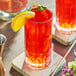 A close-up of a Lyre's Orange Sec non-alcoholic liqueur in a glass with a slice of orange on the rim.