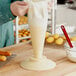 A hand holding an ivory plastic cone on a table.