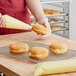 A person using a pastry bag to fill doughnuts with Rich's Allen Bavarian Creme.