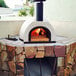 A WPPO Tuscany wood-fired outdoor pizza oven with a fire inside.