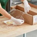 A person wearing gloves and plastic wrapping a box with Western Plastics perforated film.