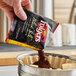 A packet of Folgers Black Silk ground coffee being poured into a coffee filter.