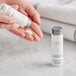 A person holding a small white bottle of Babor Energizing Lime & Green Tea lotion.