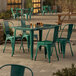 An emerald green Lancaster Table & Seating outdoor table with chairs on a patio.