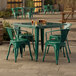 An emerald green Lancaster Table & Seating outdoor table with four green chairs on a stone patio.