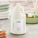 A white jug of Babor Energizing Lime & Green Tea lotion sitting on a counter next to towels.
