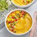 Two bowls of Dole mango chunks with yellow soup and garnish.