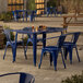 A blue metal Lancaster Table & Seating outdoor table with chairs on a patio.