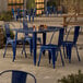 A blue Lancaster Table & Seating outdoor table and chairs on a patio.