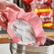 A hand holding a pre-measured coffee filter pack above a coffee maker basket.