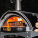 A WPPO stainless steel wood fire pizza oven with countertop base and a fire inside.