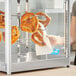 A woman putting pretzels in a display rack on a counter.