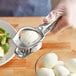 A hand using the Fox Run stainless steel egg slicer to slice a hard boiled egg.