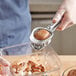 A person using a Fox Run stainless steel hand-held egg and mushroom slicer to slice mushrooms.