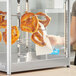 A woman putting pretzels on a ServIt countertop display rack.