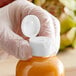 A hand holding a plastic bottle of orange liquid with a white flip top lid.