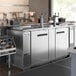An Avantco stainless steel kegerator with double taps on a large stainless steel counter.