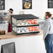 A man reaching for food in a ServIt countertop heated display case.