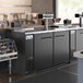 An Avantco black kegerator with a quadruple tap tower on a large counter.